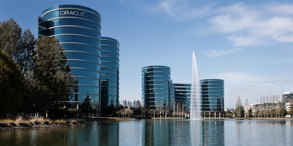 Oracle’s glass office towers rise beside a lake and fountain at the company’s corporate campus.